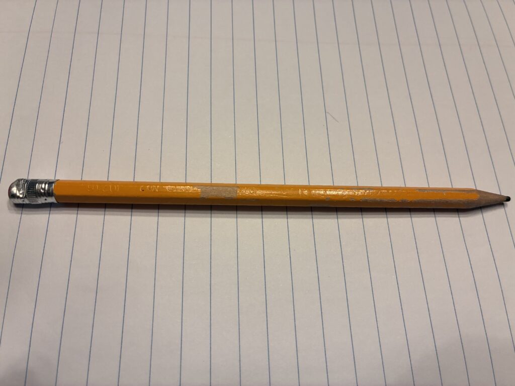 Yellow pencil resting across a lined notebook page.